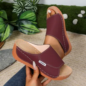 Macro view of burgundy wedge slippers featuring decorative white stitching and durable thick sole