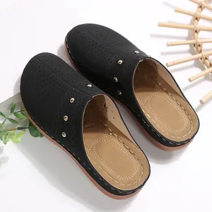 Gedetailleerde weergave van zwarte dames platform slippers met gatenpatroon.