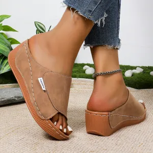 Close-up of brown suede platform wedge slippers with white stitching and FASHION tag.