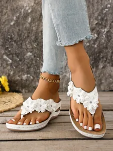 White wedge thong sandals with decorative floral patterns and rhinestone accents
