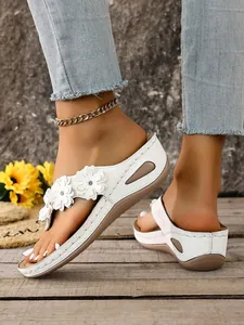 Elegant white wedge thong sandals with 3D flower decorations for a stylish summer look.