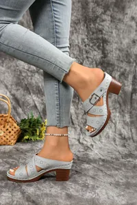 Light blue laser-cut mule sandals with chunky heel and buckle strap on model
