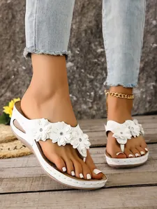 Detailed shot of women's white platform flip-flops featuring elegant 3D flower decorations