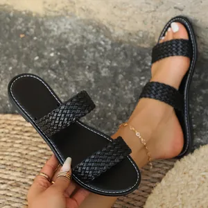 Detailopname van zwarte slippers met gevlochten bandjes en wit contraststiksel