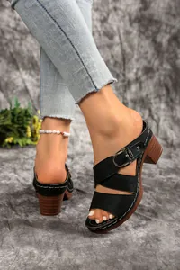 Detail of black high heel sandals with laser-cut patterns and a silver buckle strap.