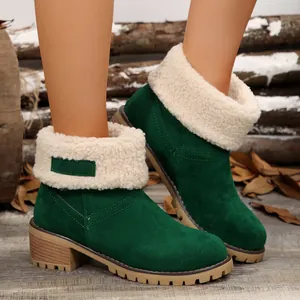 Close-up of green suede winter boots featuring white faux shearling cuffs and lug soles