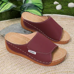 Burgundy wedge slippers with elegant white stitching and a comfortable platform sole.