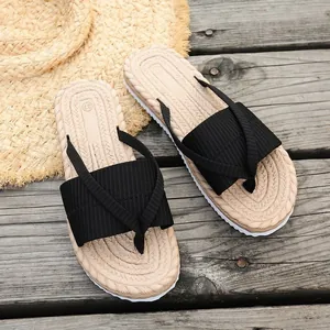 Detailed view of women's summer flip-flops with faux-straw footbed and black thong straps.