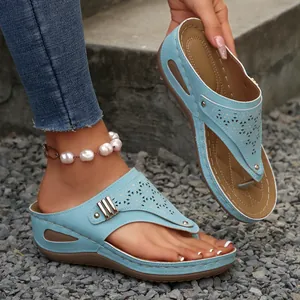 Detail of light blue wedge flip-flops featuring laser-cut patterns and platform sole