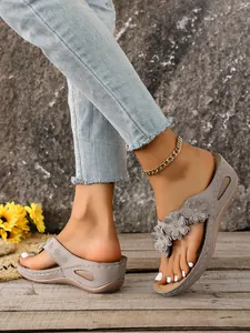 Detail view of grey wedge flip-flops featuring 3D floral accents and contrast stitching.