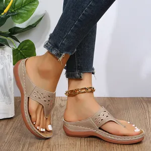 Detalle de sandalias de cuña beige con diseño de pedrería y calados intrincados