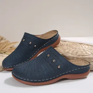 Detail van donkerblauwe suède klompen met lasergesneden patronen en gouden studs