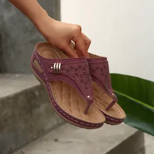 Detail view of purple wedge thong sandals with laser-cut hollow patterns and quilted footbed.