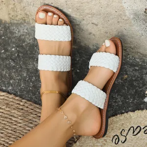 Macrodetail van modieuze witte gevlochten platte sandalen met dubbele band voor dames