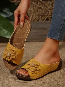 Detailed view of yellow wedge sandals with intricate flower decoration and stitching