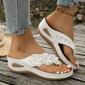 Vista detallada de chanclas de cuña blancas con detalles florali y pedrería