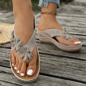 Primer plano de sandalias de cuña grises con elegantes y modernos detalles florales.