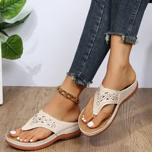 Detalle de sandalias de dedo beige para mujer con diseño calado y suela de cuña