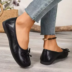 Detail view of comfortable black ballet flats with a small bow and soft leather texture.