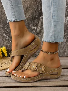 Close-up detail of women's stylish wedge thong sandals featuring decorative flowers.