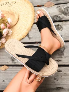 Close-up of women's black ribbed thong sandals with straw-textured flat soles