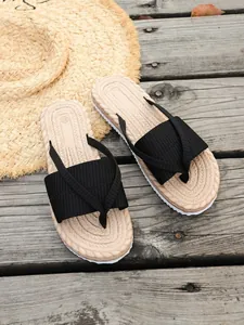 Detail view of women's beach flip-flops with black ribbed straps and woven footbed texture.