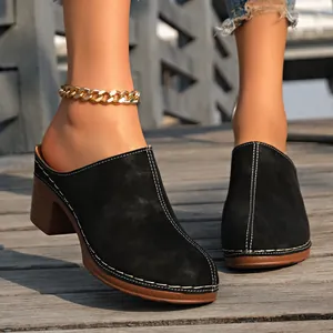 Vue détaillée de mules en daim noir avec coutures blanches contrastées et talons épais