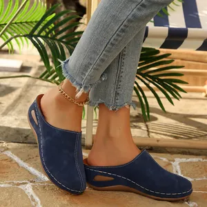 Side view of navy blue closed-toe platform mules with white stitching on stone pavement