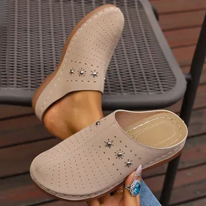 Detail of perforated beige women's wedge mules with metal studs and decorative stitching