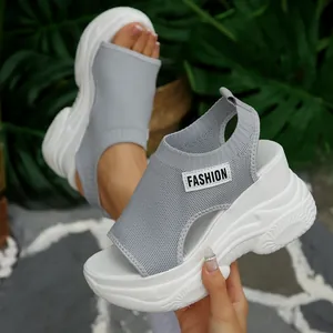 Detailopname van lichtgrijze gebreide sandalen met sleehak, platformzool en mode-label