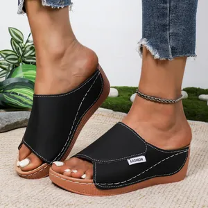Detailopname van zwarte platform sleehak sandalen met witte stiksels en peep-toe