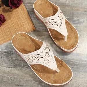 Detalle de sandalias de cuña beige con diseño calado y elegantes adornos de pedrería.