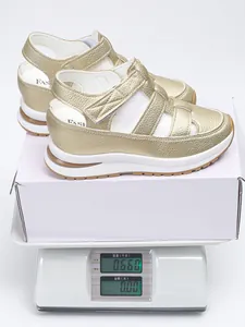 Gold hollow out wedge sandals weight display on electronic scale with white shoebox