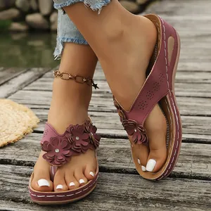 Vista detallada de chanclas con cuña moradas y flores en un muelle