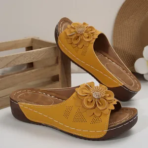 Vista detallada de sandalias con cuña amarillas con gran decoración floral 3D