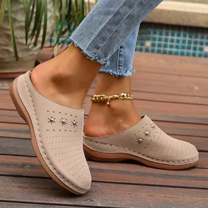 Close-up view of beige women's platform mules featuring perforated details and metal studs