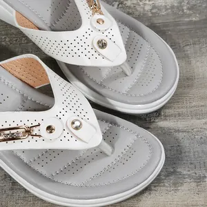 Vue détaillée de sandales compensées blanches pour femmes avec boucle dorée et strass
