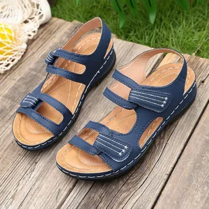 Blauwe dames sport sandalen met klittenband en witte stiksels op houten achtergrond