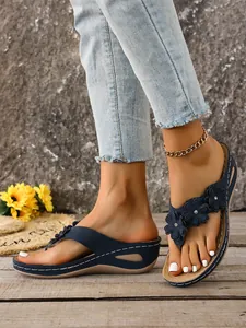 Detail view of navy blue wedge flip-flops with floral charms and rhinestone on feet