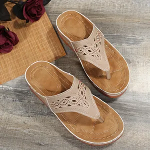 Detalle de sandalias de cuña beige para mujer con calados y adornos de pedrería.