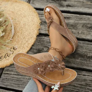 Elegantes chanclas de cuña marrones con tres flores en 3D para un look de verano ideal.
