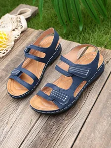 Detailweergave van blauwe dames Romeinse sandalen met contraststiksels en zachte zool.