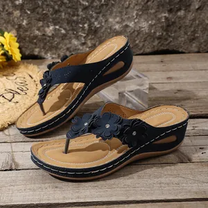 Detailed view of navy blue wedge thong sandals with three decorative leather flowers.