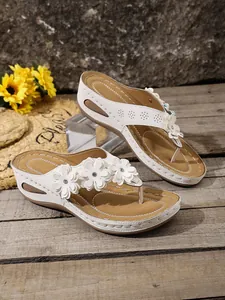 Elegant white wedge flip-flops with delicate flower decorations for casual summer wear