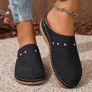 Close-up view of black women's wedge mules with perforated patterns and silver studs