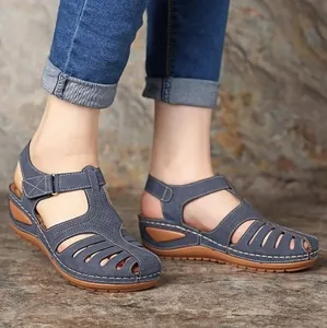 Makroansicht von blauen Retro-Keilsandaletten für Damen auf steinigem Hintergrund.