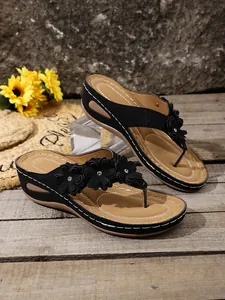 Stylish women's black wedge flip-flops with floral details and comfortable brown footbed