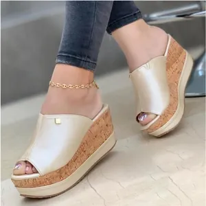Detailed view of stylish gold platform wedge mules featuring a textured cork sole on model