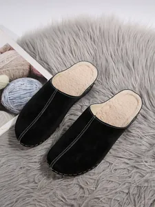 Close-up detail of black platform mules showing the warm fuzzy lining and decorative stitching