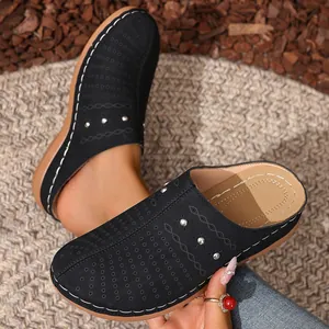 Detail view of black perforated platform mules with contrast stitching and silver studs